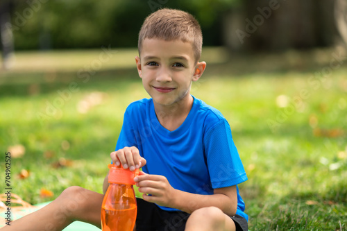 Cute boy in blue tshirt with orange bottle in hands photo