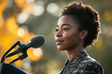 African American confident adult woman speaker speaking at podium outdoors. Side view of a female politician or president speaking into a microphone