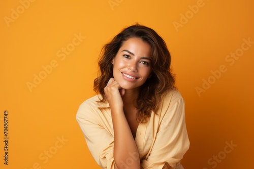 Portrait of smiling young woman looking at camera isolated on orange background