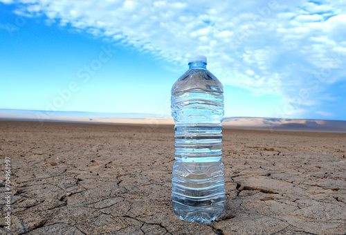 Mineral water on Drought land. Global drought. Plastic bottle with water on Dry cracked earth. Water crisis and World Climate change. Dried earth in Water crisis in nature. No freshwater in ocean.