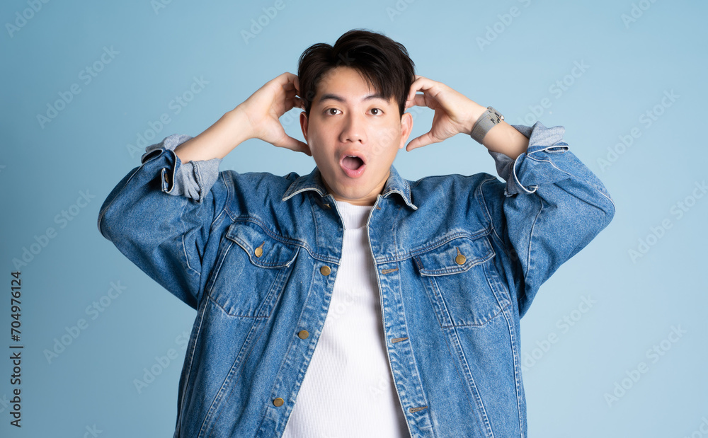Portrait of an Asian guy wearing a jacket posing on a blue background Portrait of an Asian guy wearing a jacket posing on a blue background