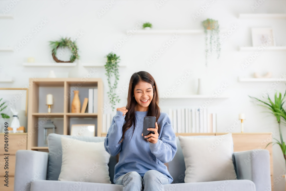 Happy young asian woman relax on comfortable couch at home texting messaging on smartphone, smiling girl use cellphone, chatting online message, shopping online from home Happy young asian woman relax on comfortable couch at home texting messaging on smartphone, smiling girl use cellphone, chatting online message, shopping online from home