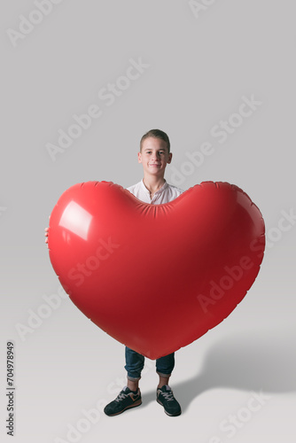Cute boy with heart shaped balloon on bright background. Love concept. © Paopano