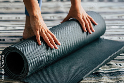 Yoga at home active lifestyle woman rolling exercise mat in living room for morning meditation yoga concept background - healthy people in daily sport exercise fitness activity photo
