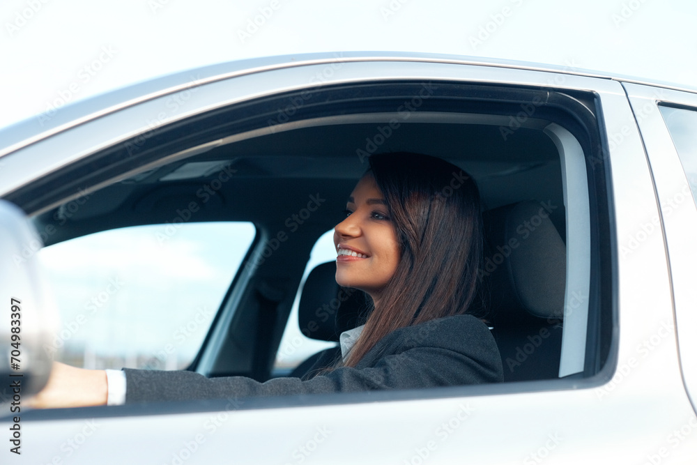 Beautiful young happy smiling woman driving her new car.