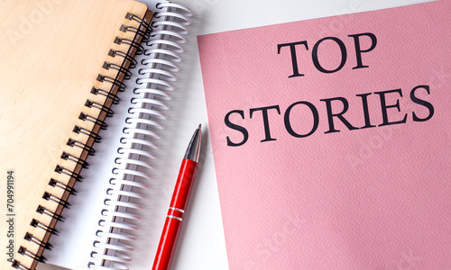 TOP STORIES word on the pink paper with office tools on white background