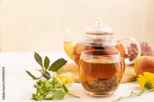 Red tea with herbs in glass teapot on white wooden. Top view, selective focus.