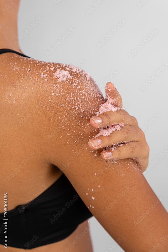 Fototapeta premium Woman applying scrub cosmetics on her skin on her shoulder