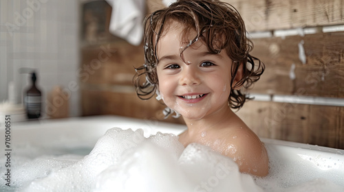 Little preschooler boy play with foam in bathtub 