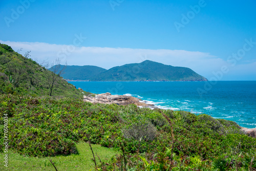 ocky coastline with turquoise-green water, green slopes and an absolutely blue sky.