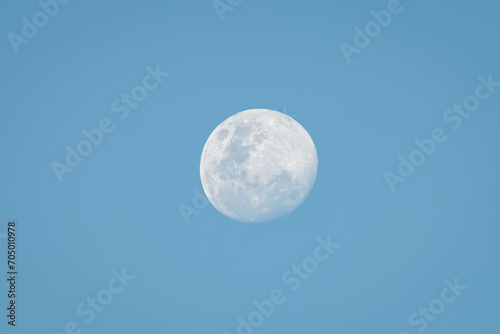 White full moon against blue sky  with clear sky and moon details.