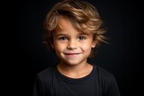 Portrait of a cute little boy with blond hair on black background