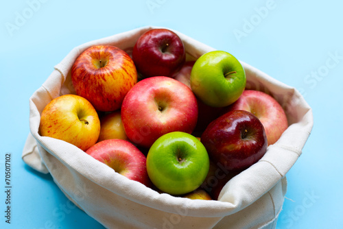 Variety of fresh apples on blue background.