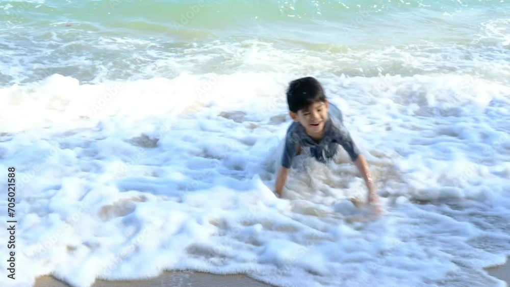 Little Asian boy playing in the sand at the sea beach