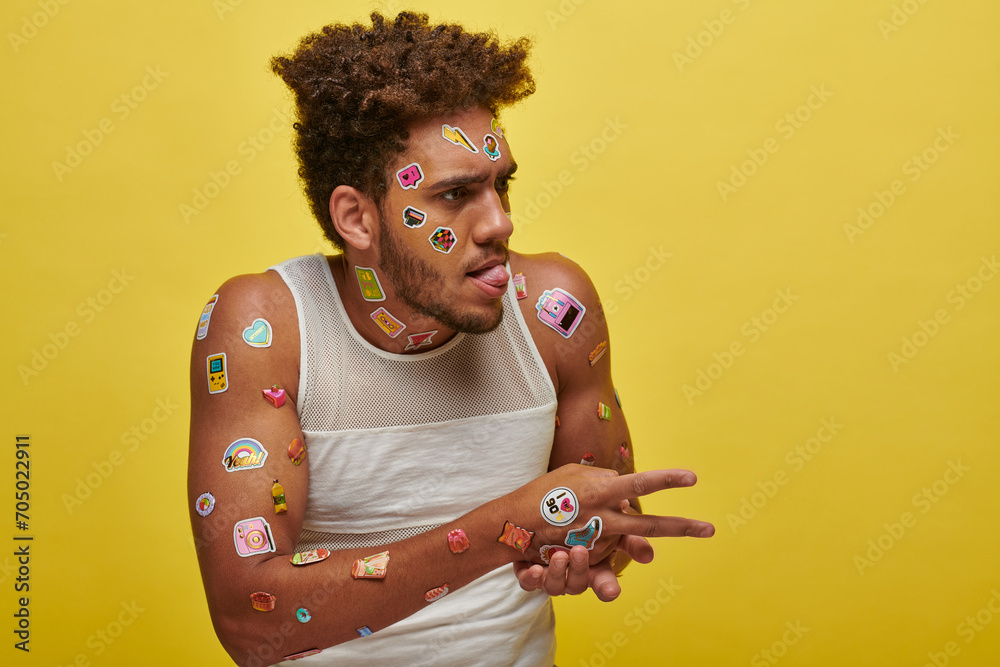 funny african american guy in tank top with stickers on face sticking out tongue on green backdrop - obrazy, fototapety, plakaty 
