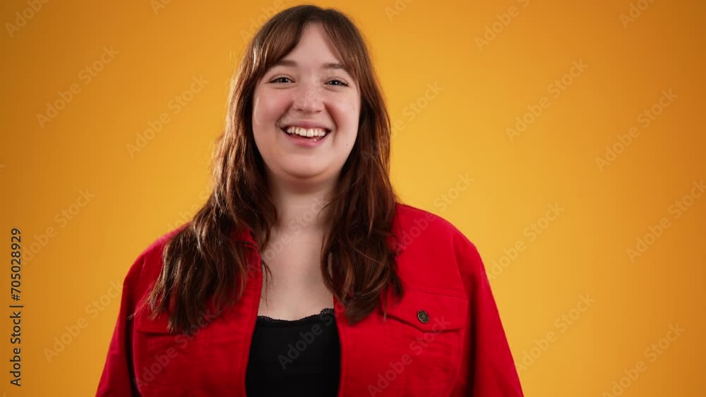 Young smiling woman 20s wearing red jacket waving meet greet with hand as notices someone isolated on plain yellow background studio. People portrait lifestyle concept Young smiling woman 20s wearing red jacket waving meet greet with hand as notices someone isolated on plain yellow background studio. People portrait lifestyle concept