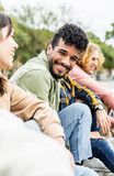 Vertical photo. Diverse group of young people laughing together. Hispanic latin man smiling at camera while having fun with multiracial friends in city street. Friendship concept.