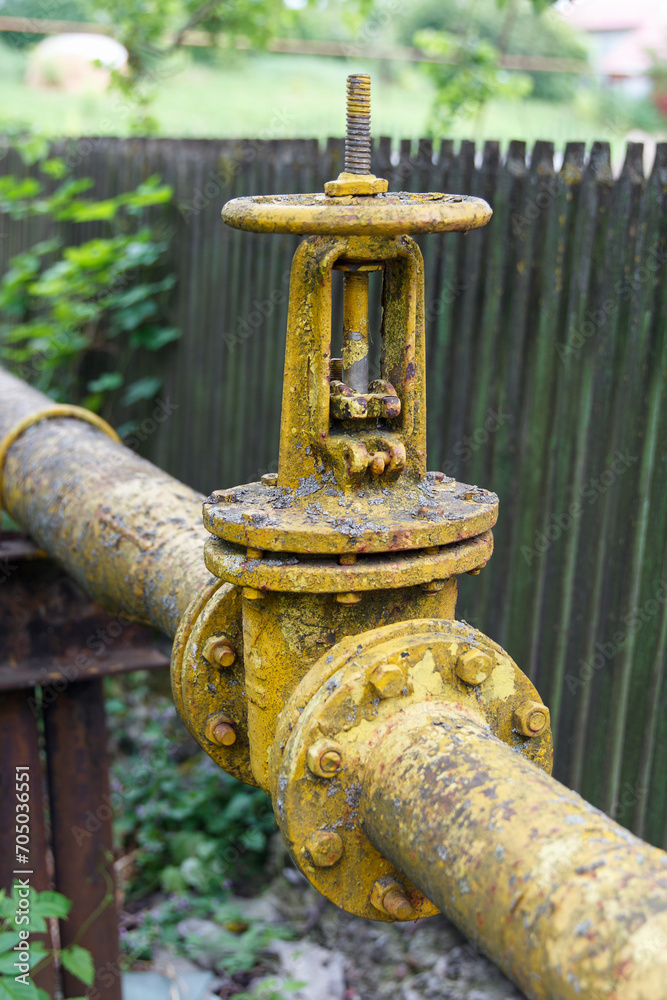 Gas pipe with big old valve-crane. Industrial gas pipeline laid along fence, gasification of population. Gas pipe with big old valve-crane. Industrial gas pipeline laid along fence, gasification of population.