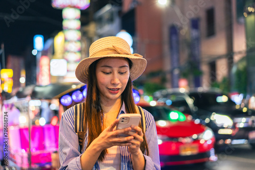 Young Asian woman traveler tourist using a mobile phone in China town night market in Bangkok in Thailand - people traveling enjoying journey life concept