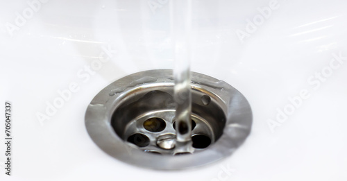 A close up photo captures a water drain in a sleek sink, with clear water flowing effortlessly from the faucet. The minimalist design highlights the efficient water drain.