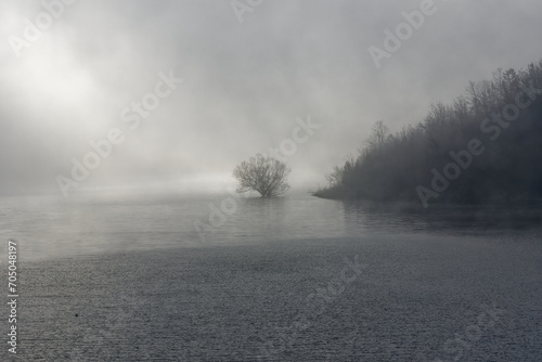 Panoramic view of Lake Turano. Lake in the mystical fog. Winter landscape with town on the rock. Connection bridge over the water with plants and leaves where legends can be told photo