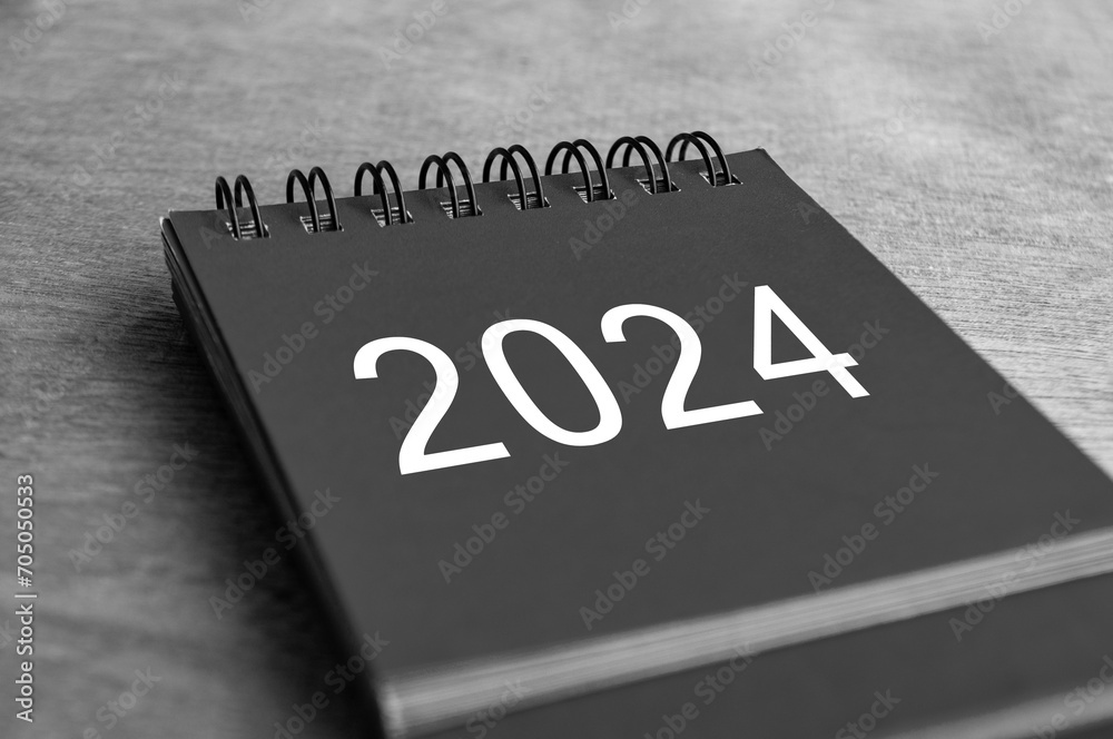Fototapeta premium Black and white Year 2024 desk calendar on wooden desk. New Year and calendar concept