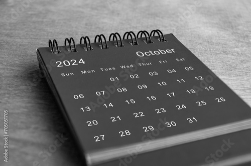 Black and white October 2024 desk calendar on wooden desk. New month and calendar concept