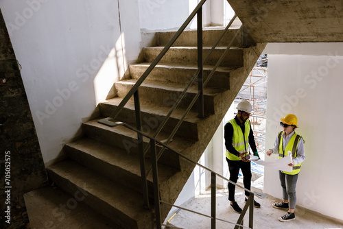 Engineers and Architect Caucasian looking at blueprint of building construction, planning the work in a professional. inspector is looking at steel structure and materials at construction site. photo