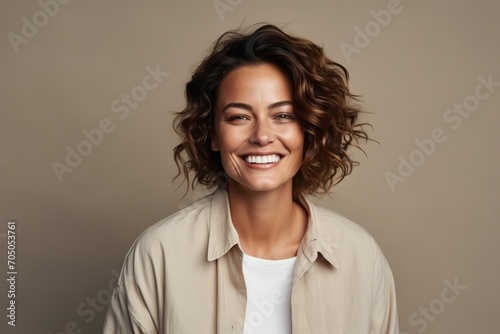 Portrait of a happy young woman with curly hair smiling at camera © Loli