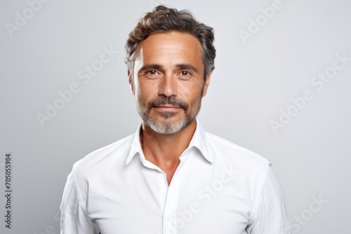 Handsome mature man in a white shirt on a grey background