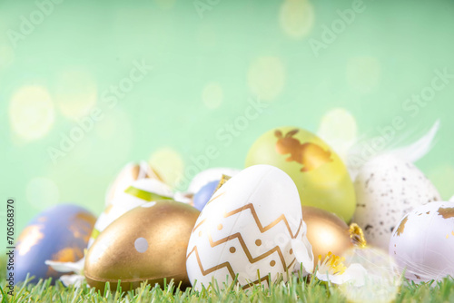 Easter egg and grass background. Funny colorful Easter eggs with bunny rabbit decor and sunny bokeh on grass and light green background. Happy Easter spring holiday greeting card background