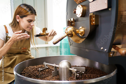 Professional coffee roaster working with modern automated roasting machine in the coffee roasting factory. 