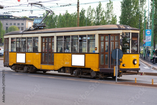 Billboards on an old yellow tramway in Milan.