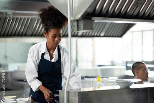 Happy African American woman standing with arms crossed while working as chef in a restaurant. Cooking class. culinary classroom. happy young african woman students cooking in cooking school. photo