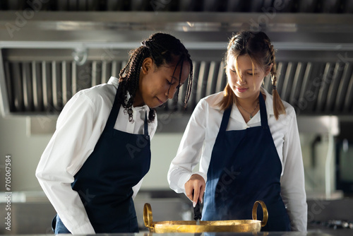 portrait two young african and caucasian woman cooking student. Cooking class. culinary classroom. group of happy young woman multi - ethnic students focusing on cooking lessons in a cooking school. photo