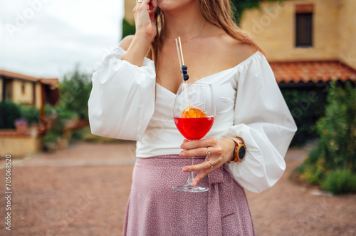 Close up of female hands holding glasses of acohol cocktail with fresh fruts and berries photo