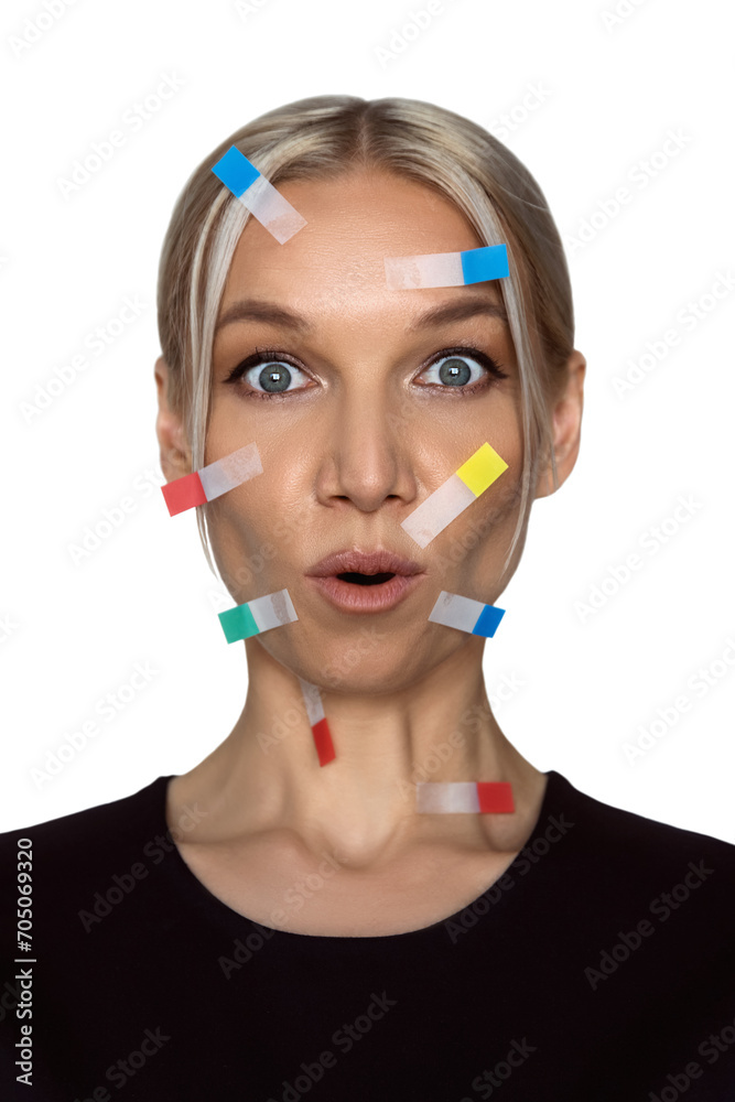 young beautiful caucasian woman blonde with surprised look looks into the camera with colorful stickers on her face, isolated on white, creative concept of copywriter or freelancer young beautiful caucasian woman blonde with surprised look looks into the camera with colorful stickers on her face, isolated on white, creative concept of copywriter or freelancer