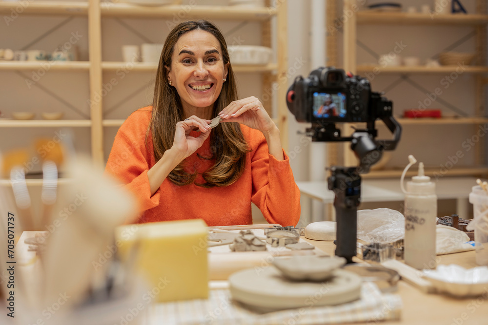 smiling adult influencer woman records herself to give tutorials with her camera smiling adult influencer woman records herself to give tutorials with her camera