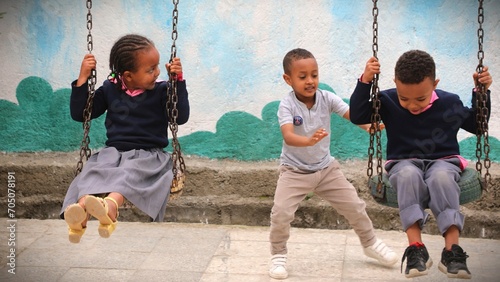 Children Having Fun on Swings with Colorful Mural