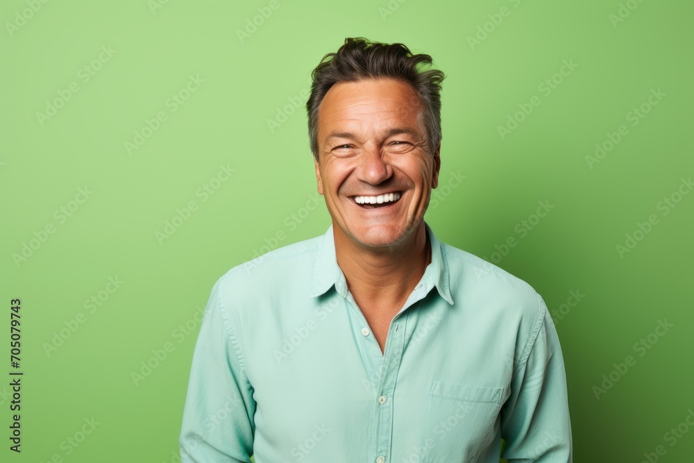 Portrait of happy mature man laughing and looking at camera over green background Portrait of happy mature man laughing and looking at camera over green background