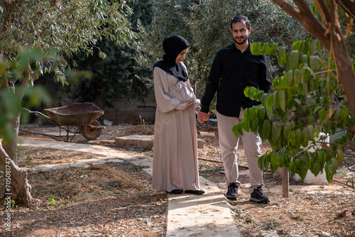 A husband walks with his pregnant wife in the park, exchanging loving glances and feeling excited about the approaching time of birth