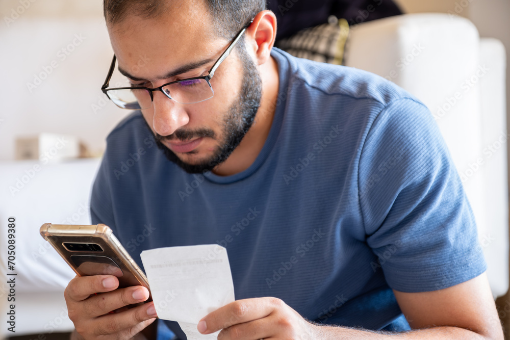 young bearded man making call while holding receipts young bearded man making call while holding receipts