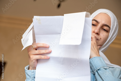 Young Female wearing hijab in the living room checking receipts © nooh