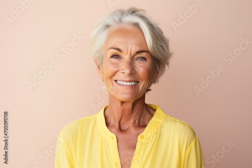 Portrait of happy senior woman looking at camera on pink background.