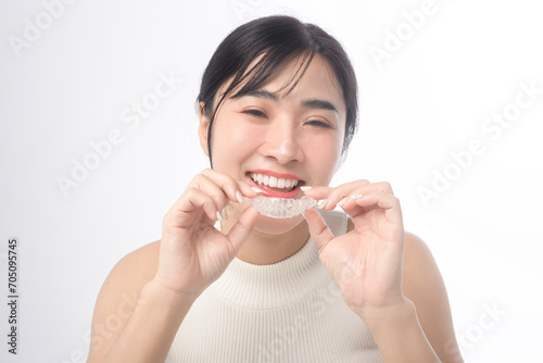 Young smiling woman holding invisalign braces over white background studio, dental healthcare and Orthodontic concept..