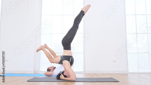 Young couple practicing yoga in a white room of studio.
