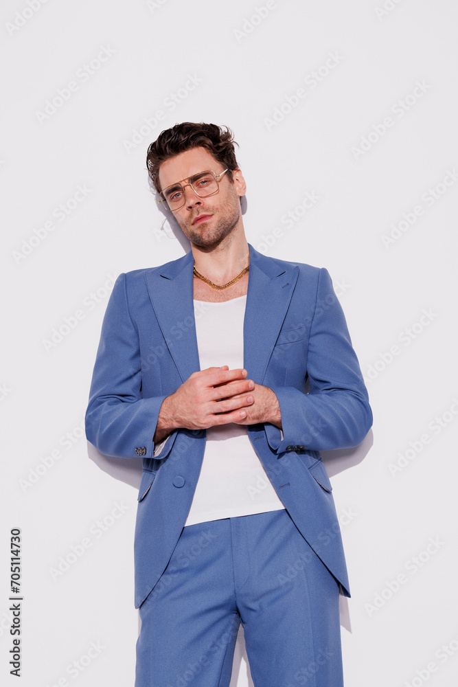 Confident and stylish brunette man in blue suit and eyeglasses looking at camera on grey background Confident and stylish brunette man in blue suit and eyeglasses looking at camera on grey background