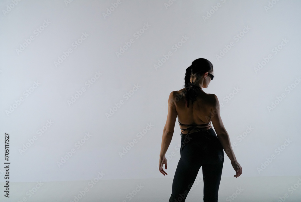 Fototapeta premium Young woman in black revealing clothes posing on white studio background. Female dancer poses and shows off her slender body. The concept of the dance promo shot.