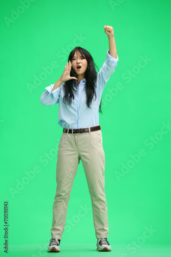 A girl in a blue shirt, on a green background, in full height, screams