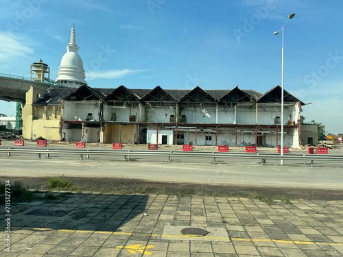 partially demolished building at Port of Colombo, Sri Lanka with Sambodhi Pagoda buddhist temple in the background